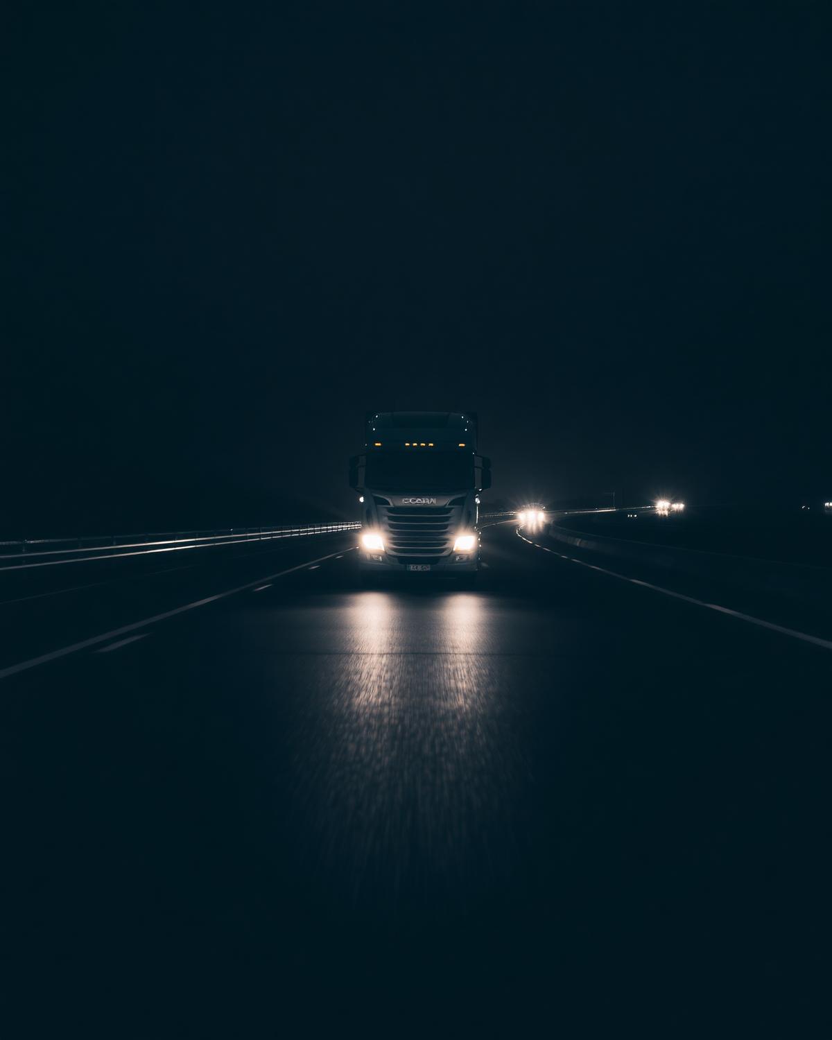 Semi truck headlights on a wet night highway